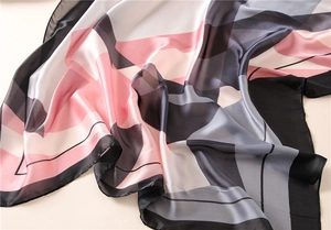 Detail of silk-feel scarf showing geometric color blocks and smooth fabric texture
