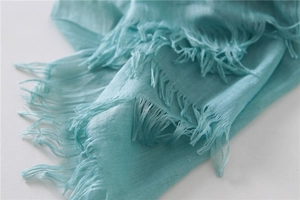 Close-up of sky blue cotton linen scarf featuring fine fabric texture and tassel fringe