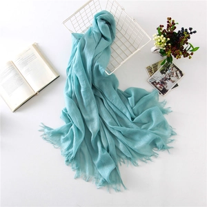 Detail of light blue linen scarf with fringe edges and lightweight translucent texture