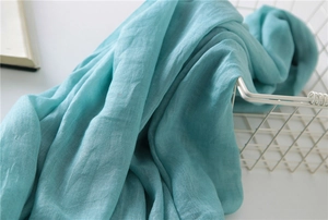 Detailed texture of turquoise cotton linen scarf draped over a white metal basket