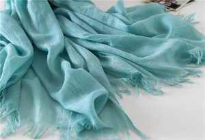 Detail of light blue cotton linen scarf showing soft fabric texture and fringe edges