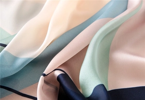 Macro detail of silk scarf showing smooth satin texture and colorful geometric patterns