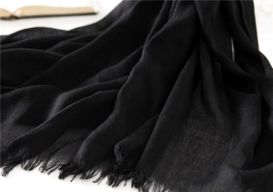 Close-up of lightweight black cotton-linen scarf with delicate frayed tassel edges