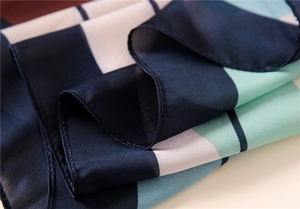 Detail of silk-like scarf featuring blue, mint green, and pink geometric stripes texture