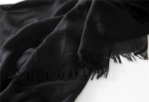 Detail view of the breathable black cotton linen scarf showing frayed fringe edges