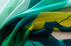 Detail of colorful geometric silk scarf showing luxury satin texture and neat hem