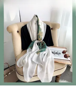 Detail of silk-like vintage shawl featuring elegant green lotus leaf patterns on pearl white