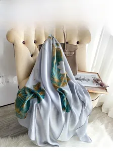 Close-up of lightweight silk scarf featuring elegant lotus floral patterns in light blue