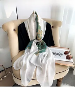 Detail of silk-like scarf with green and gold lotus leaf prints on white fabric