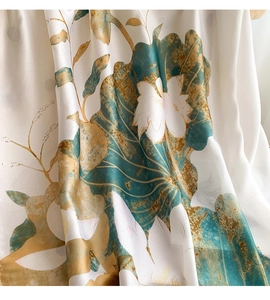 Detail of silk-like fabric showing artistic blue and gold lotus prints with soft draping
