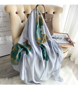Detailed view of grey-blue silk scarf with lotus print draped on a classic armchair