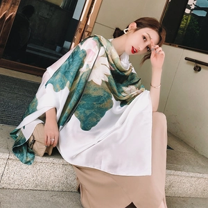 Close-up of silk scarf with lotus print and satin finish on an outdoor stone step