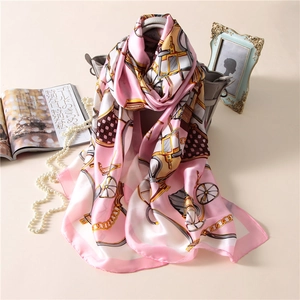 Elegant pink carriage print silk satin scarf draped on a luxury grey handbag