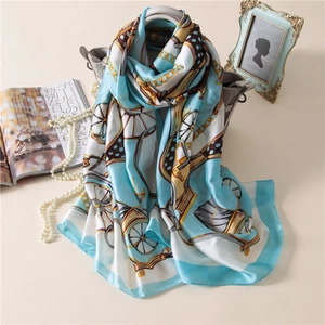 Elegant silk-like scarf with sky blue carriage and chain prints draped on a handbag