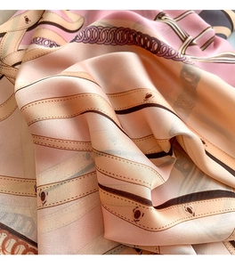 Detail of silk scarf with chain and belt buckle print in elegant pink and brown