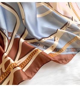 Macro detail of silk chain pattern scarf showing elegant blue and brown satin texture
