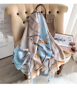 Detail of multi-color geometric print silk scarf draped over a beige armchair and handbag
