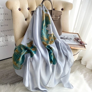 Elegant silk scarf with lotus print draped on a chair with stylish summer accessories