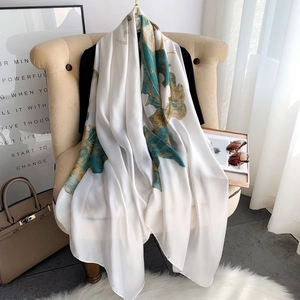 Elegant ivory silk scarf with lotus print draped on a sofa for sun protection