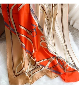 Detail of elegant chain print silk scarf with classic equestrian pattern on white rug