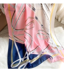 Detail of silk scarf with chain and belt patterns on a soft white faux fur rug