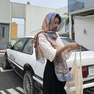 Outdoor shot of long chain-print silk scarf worn as a headscarf with retro car backdrop