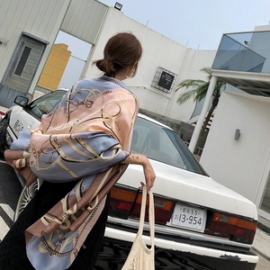 Detail of luxury chain print silk scarf draped on a vintage car in outdoor setting