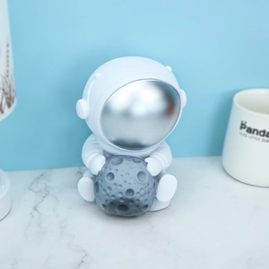 Astronaut piggy bank with silver visor sitting and holding a grey textured moon