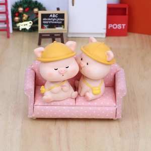 Cute shaking head piggy ornaments with yellow hats on a mini pink polka dot sofa