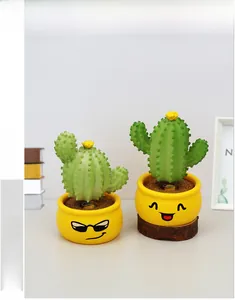 Detail of two cute cactus bobblehead ornaments with yellow smiley face pots for cars