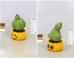 Detail of two resin cactus bobbleheads with smiling faces and pink flowers on yellow pots
