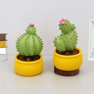 Macro detail of cactus bobblehead figures with pink flowers and metal spring on a desk