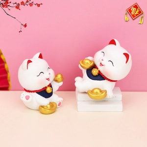 Detailed close-up of lucky cat figurines with golden ingots for car and home decor