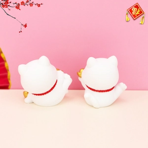 Detailed back view of white lucky cat figurines with red collars and gold coins