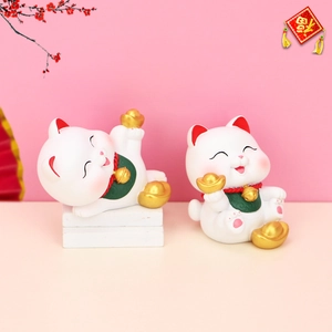 Detail view of two lucky cat figurines with gold ingots and bell collars for car decor