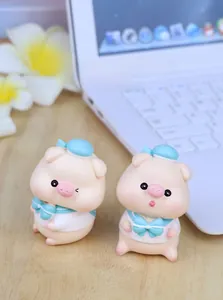 Close-up of cute resin pig figurines in sailor outfits on a wooden desk setup