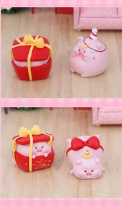 Détail de figurines de cochons roses en résine avec boîte cadeau et petit canard jaune