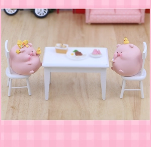 Figurines de cochons roses miniatures avec canards et petits meubles dans un décor de café