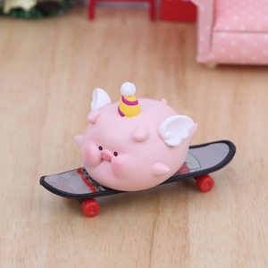 Figurine de cochon rose avec ailes et chapeau de fête sur socle de skateboard noir