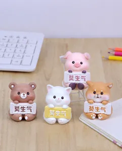 Close-up of four cute resin animal figurines holding Mo Sheng Qi signs on wood desk