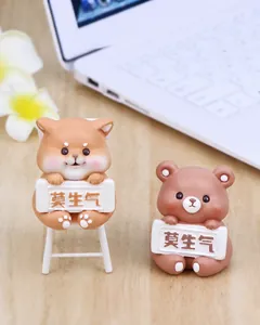 Cute resin dog and bear figurines holding calm signs on a desk with flowers