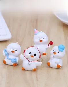 Set of four cute duck figurines with accessories on a wooden desk with a keyboard