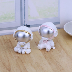 Cute resin astronaut car ornaments set in gold and pink accents on wooden dashboard