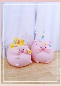 Detail of two cute pink pig figurines with party hat and duck on a wooden table