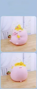 Close-up of pink pig piggy bank with crown and small duck showing coin slot detail