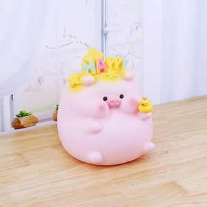 Pink cartoon pig piggy bank with Happy text and yellow duckling on a wooden desk