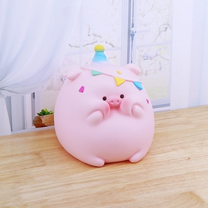 Pink cartoon pig piggy bank with party hat on wooden table in a cozy home setting