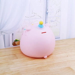 Cute pink pig piggy bank with colorful horn on a bright wooden table by the window