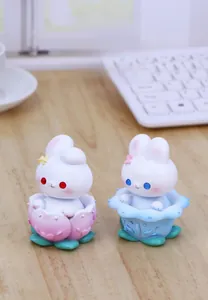 Close-up of cute rabbit ornaments with flower bases on a desk with keyboard and cup
