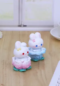 Detail of cute rabbit figurines with lotus bases in pastel pink and blue resin
